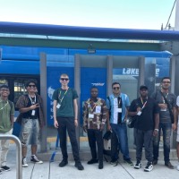 Group of students posing near Bus stop with the bus